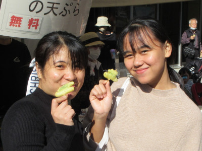 入居者が食事を楽しむ様子。野菜を手に持ち笑顔で交流している。
